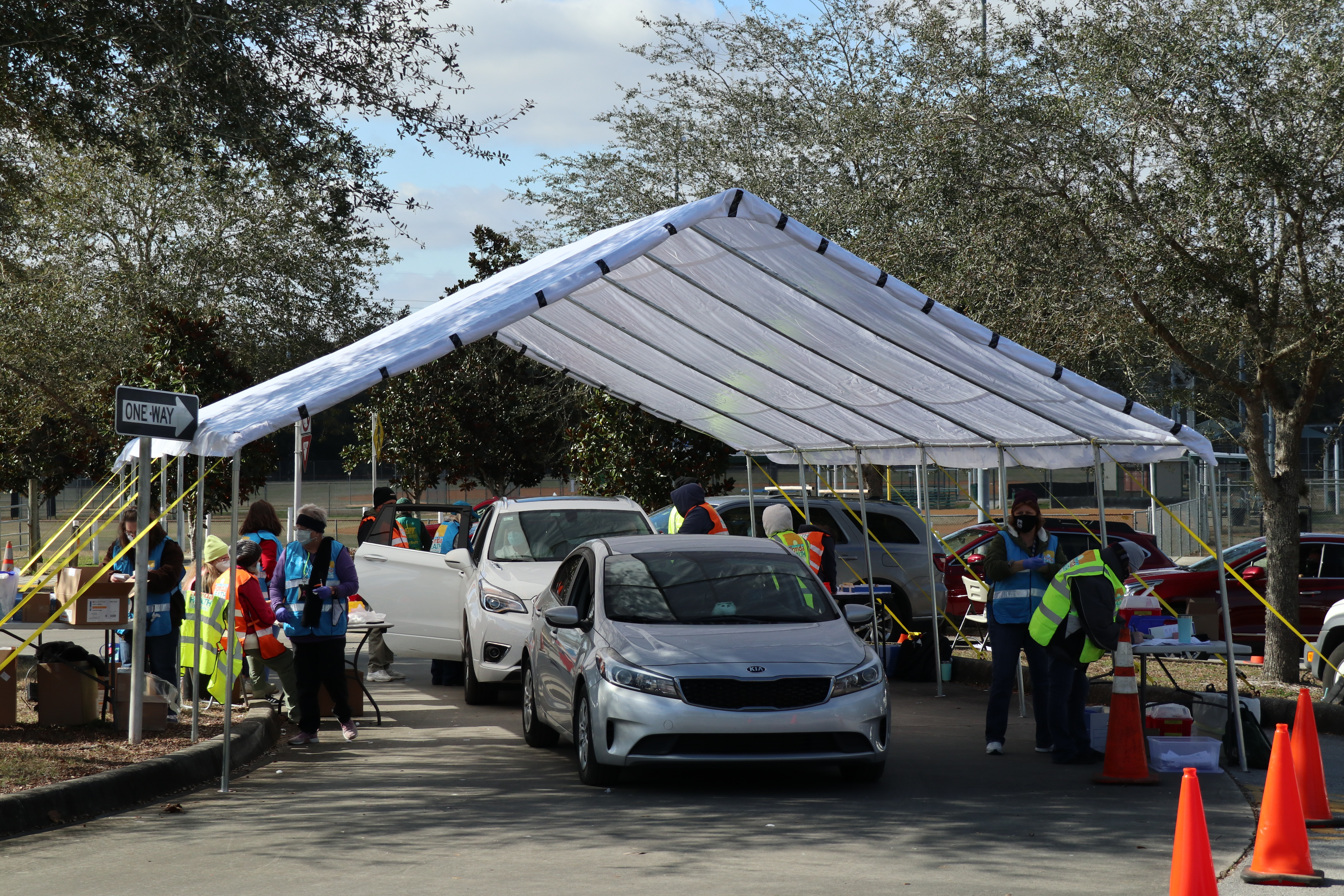 cars parked under tent for vaccinations