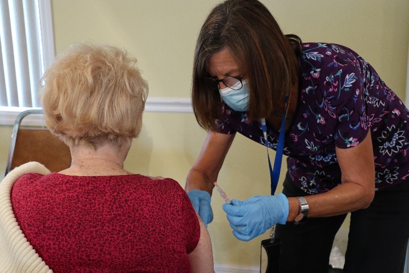 older woman receiving a vaccine from nurse