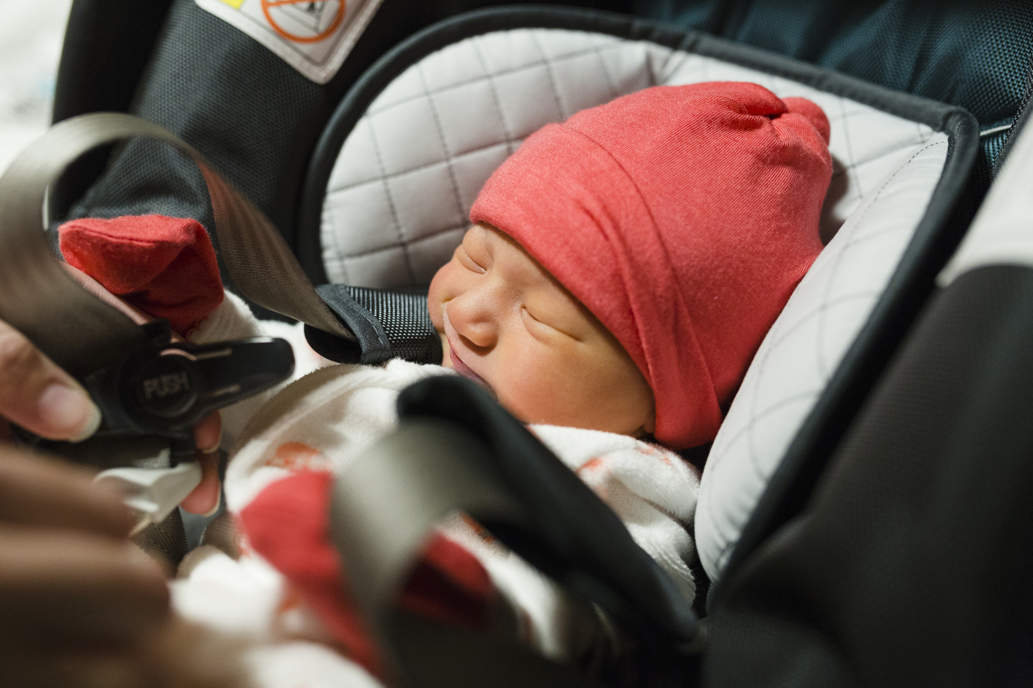 Newborn baby getting strapped into carseat
